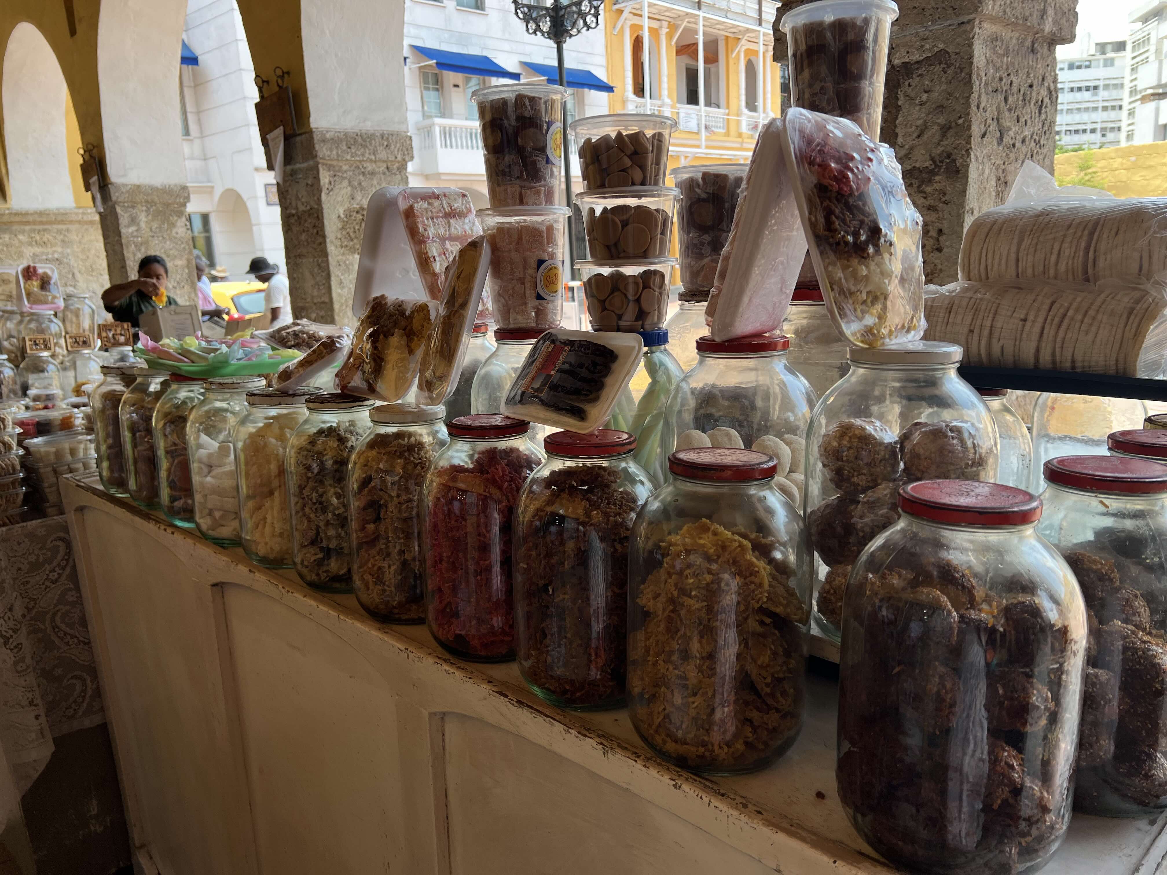 A street stall in Portal de Los Dulces displaying a variety of traditional sweets in clear glass jars.