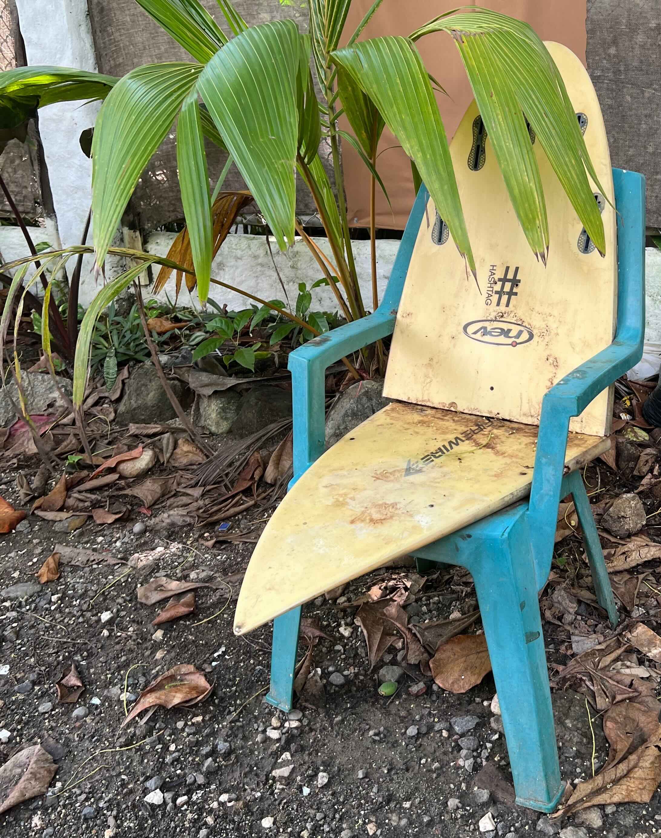 A chair made from a surfboard and plastic frame.