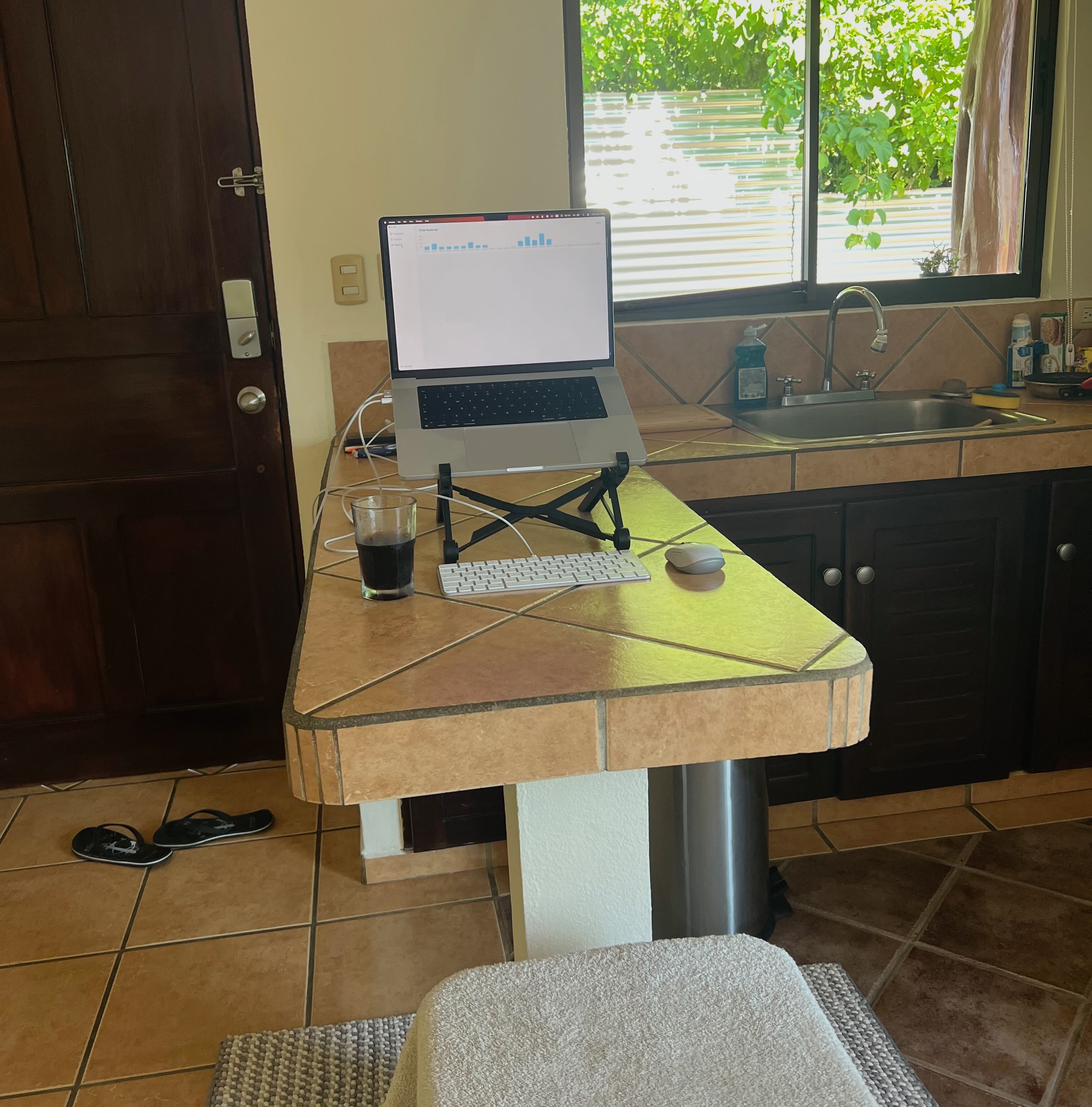 Kitchen in Costa Rica showcasing a laptop on the kitchen top with a window to the right full of greenery