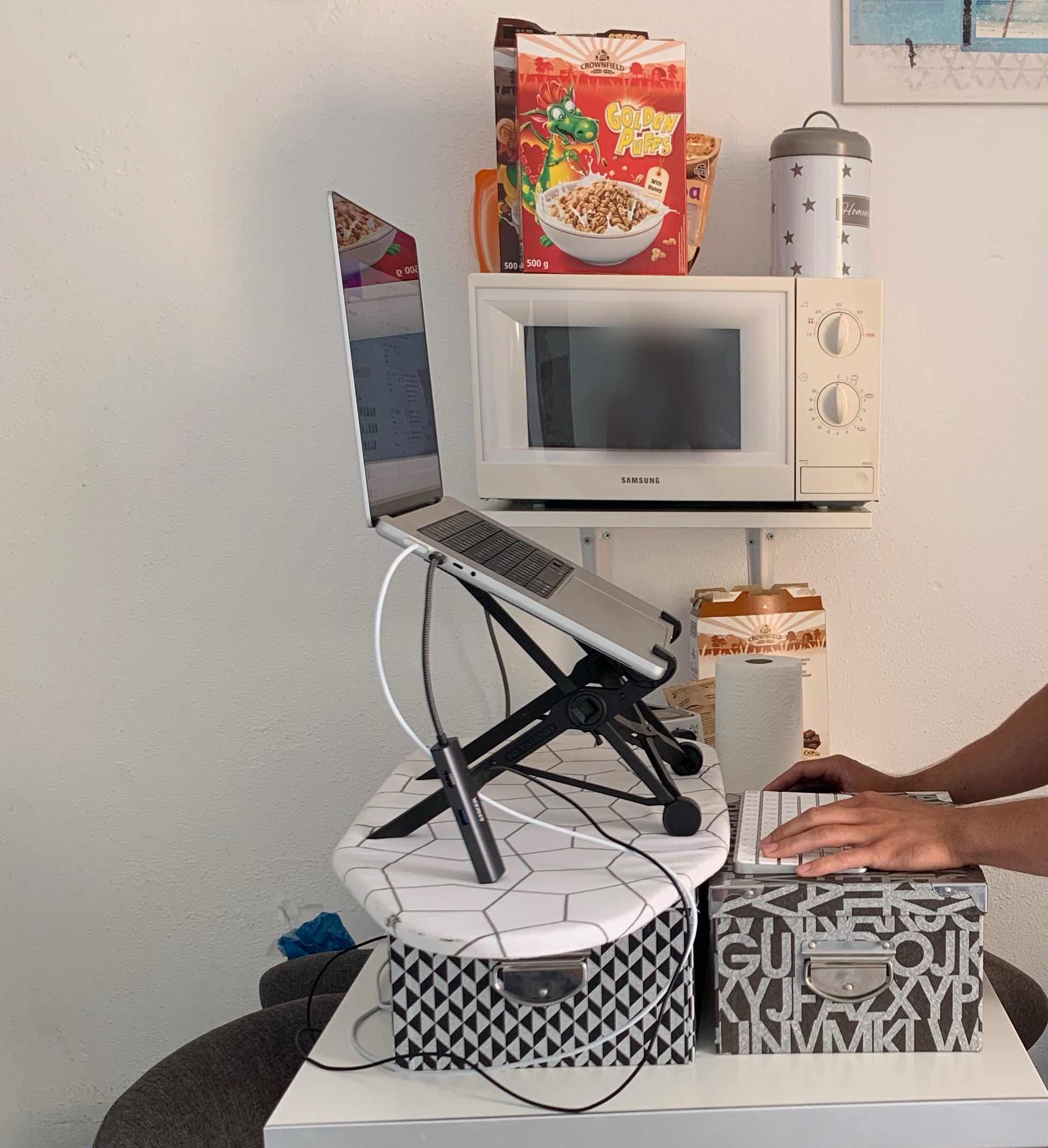 Me working on the laptop which is standing on a few boxes and an ironing board.